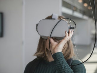 woman in black sweater holding white and black vr goggles