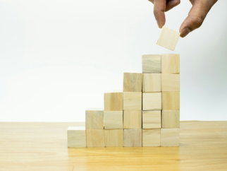 A person placing a piece of wood into a pyramid