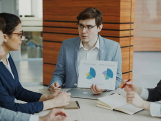 Man presenting charts to colleagues in a meeting.