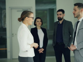 Business professionals conversing in a modern office hallway.
