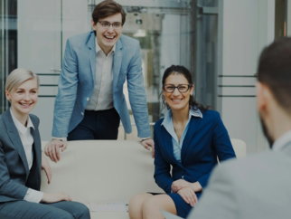 Four smiling business people in a modern office.